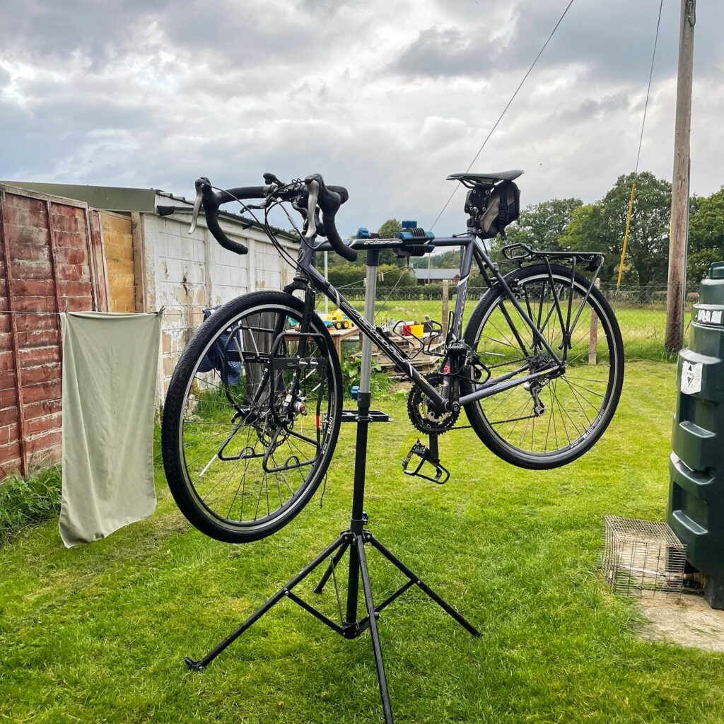 Black gravel bike with drop handlebars on bike stand. 